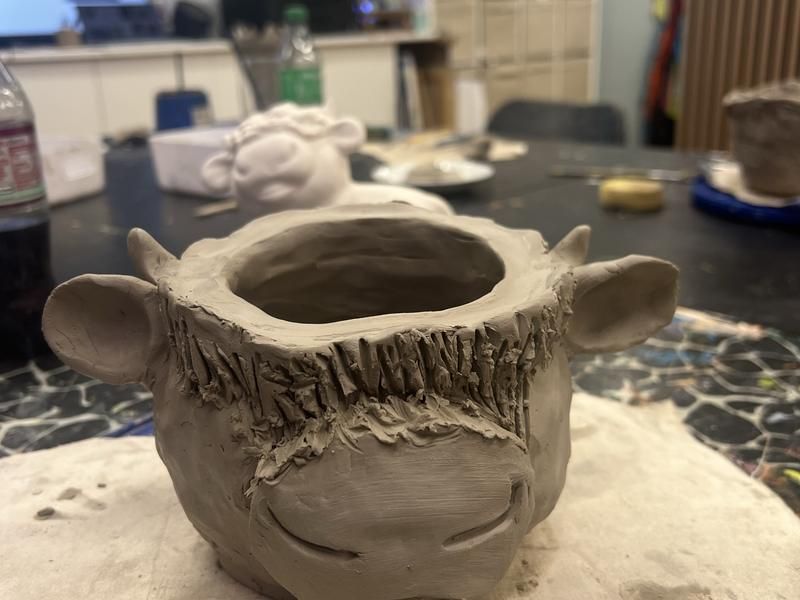 A hand-built clay highland cow pot made at a corporate clay day