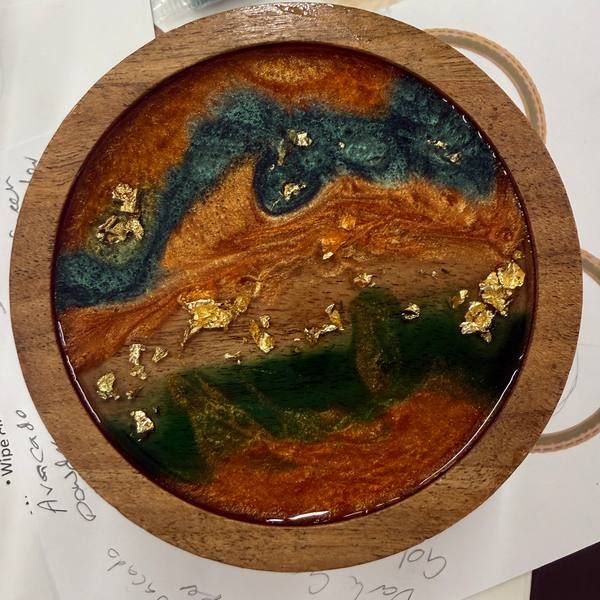 A finished resin serving board with swirls of blue, teal and gold