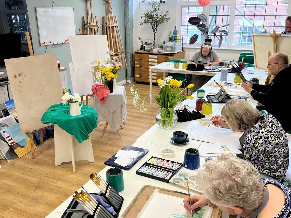 Adult students painting at easels during a watercolour class in the studio, a lavender painting on the easel