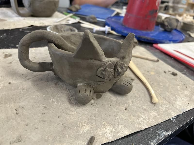 A hand-built clay cat mug made by a student at a clay workshop