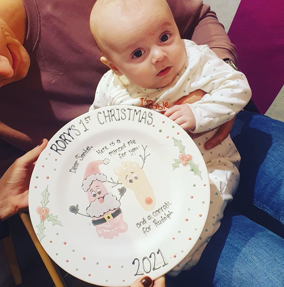 A baby with a hand- and footprint “first Christmas” keepsake plate