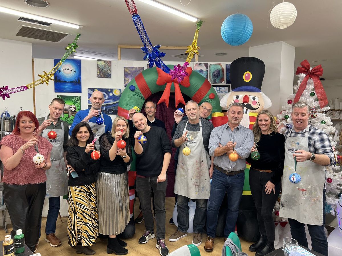 A team holding up their painted Christmas baubles